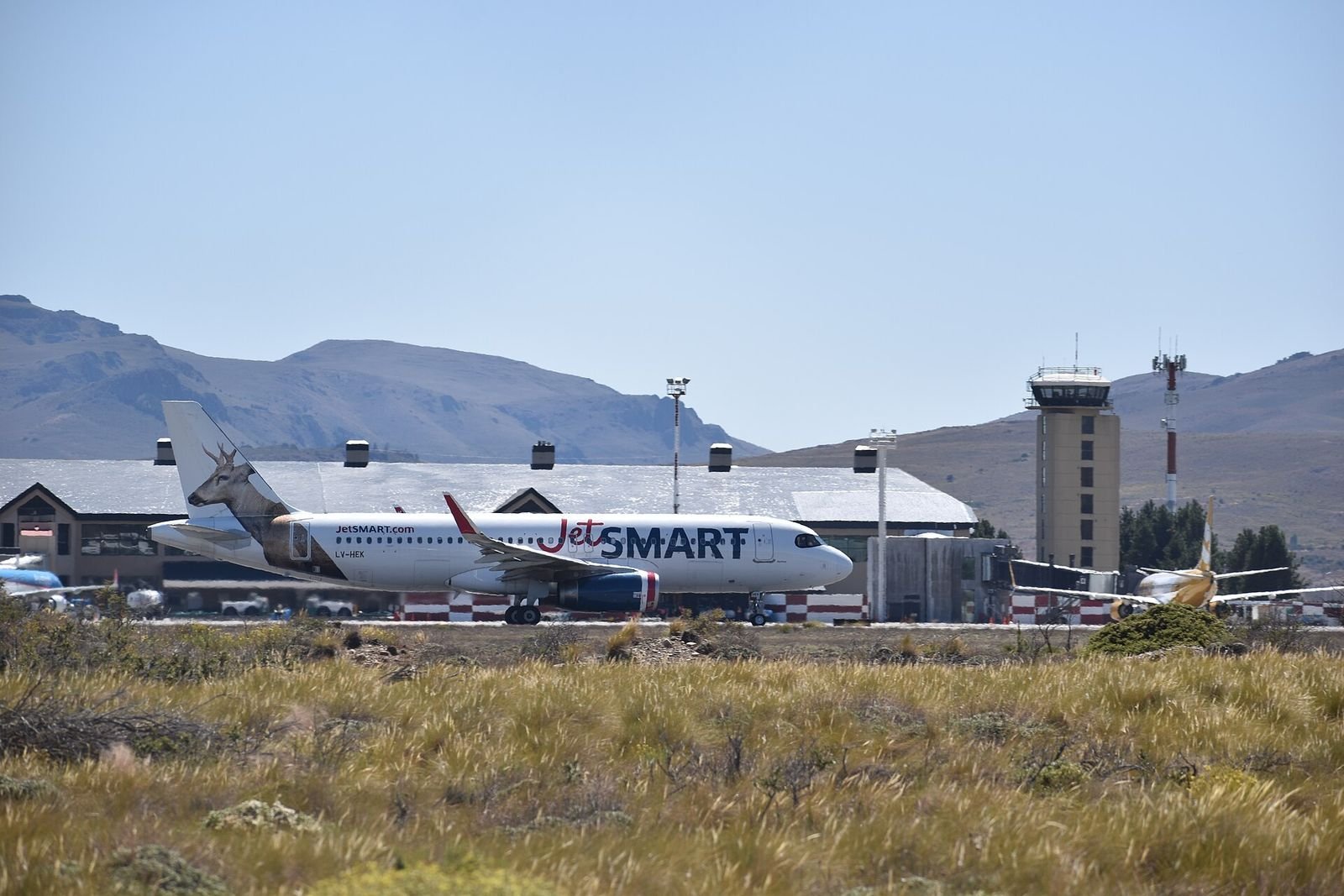 Avião na pista do aeroporto de Bariloche, com montanhas e bosque ao fundo