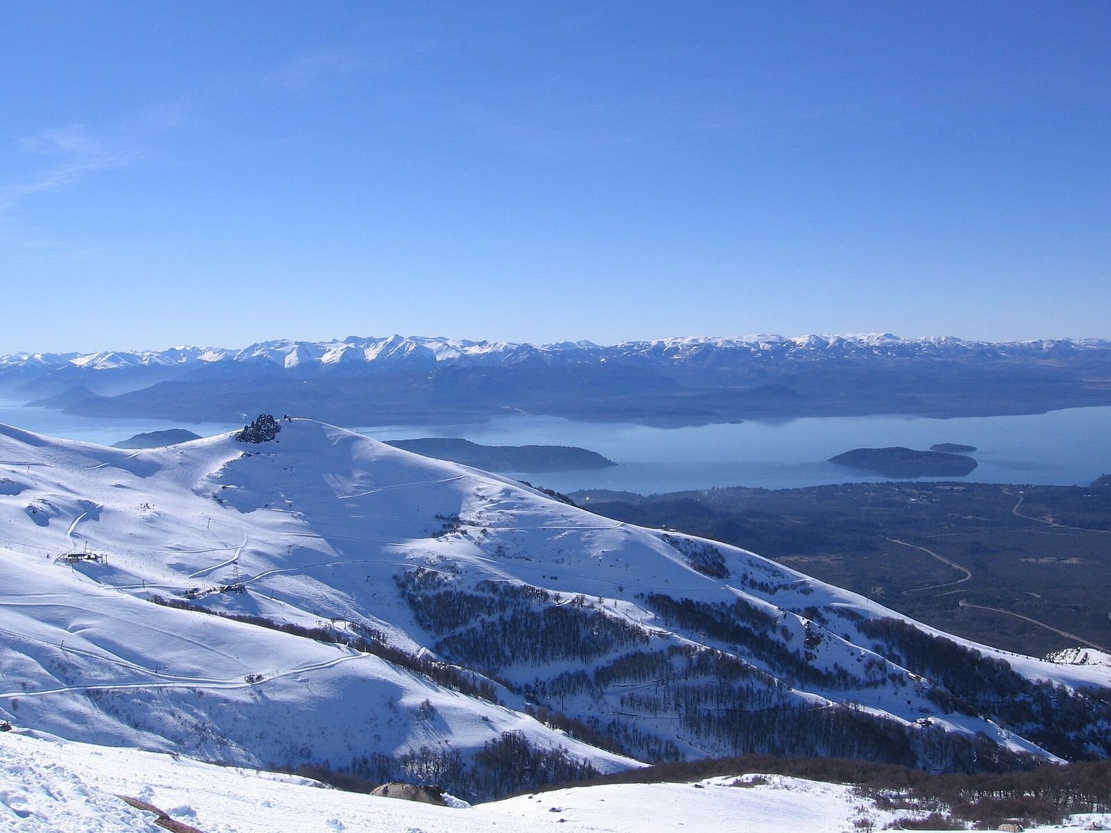 Vista do alto do Cerro Catedral nevado, com lagos e montanhas ao fundo