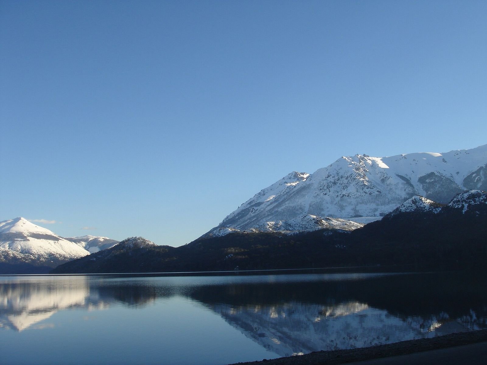 Montanhas nevadas refletidas no Lago Gutiérrez, em Bariloche